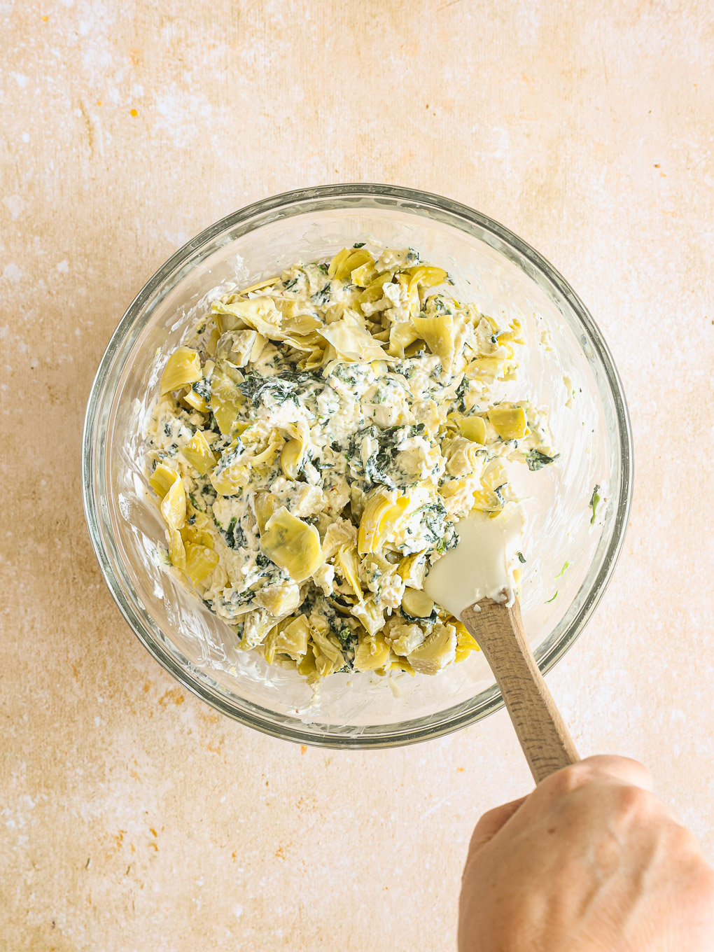 artichokes with cream cheese and spinach in a glass bowl.