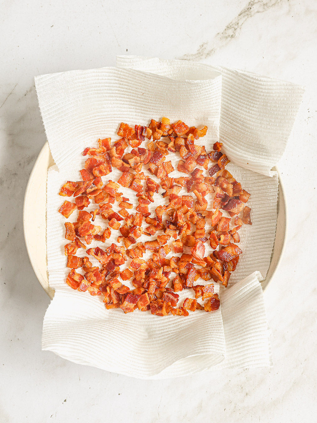 cooked bacon on a paper lined plate.
