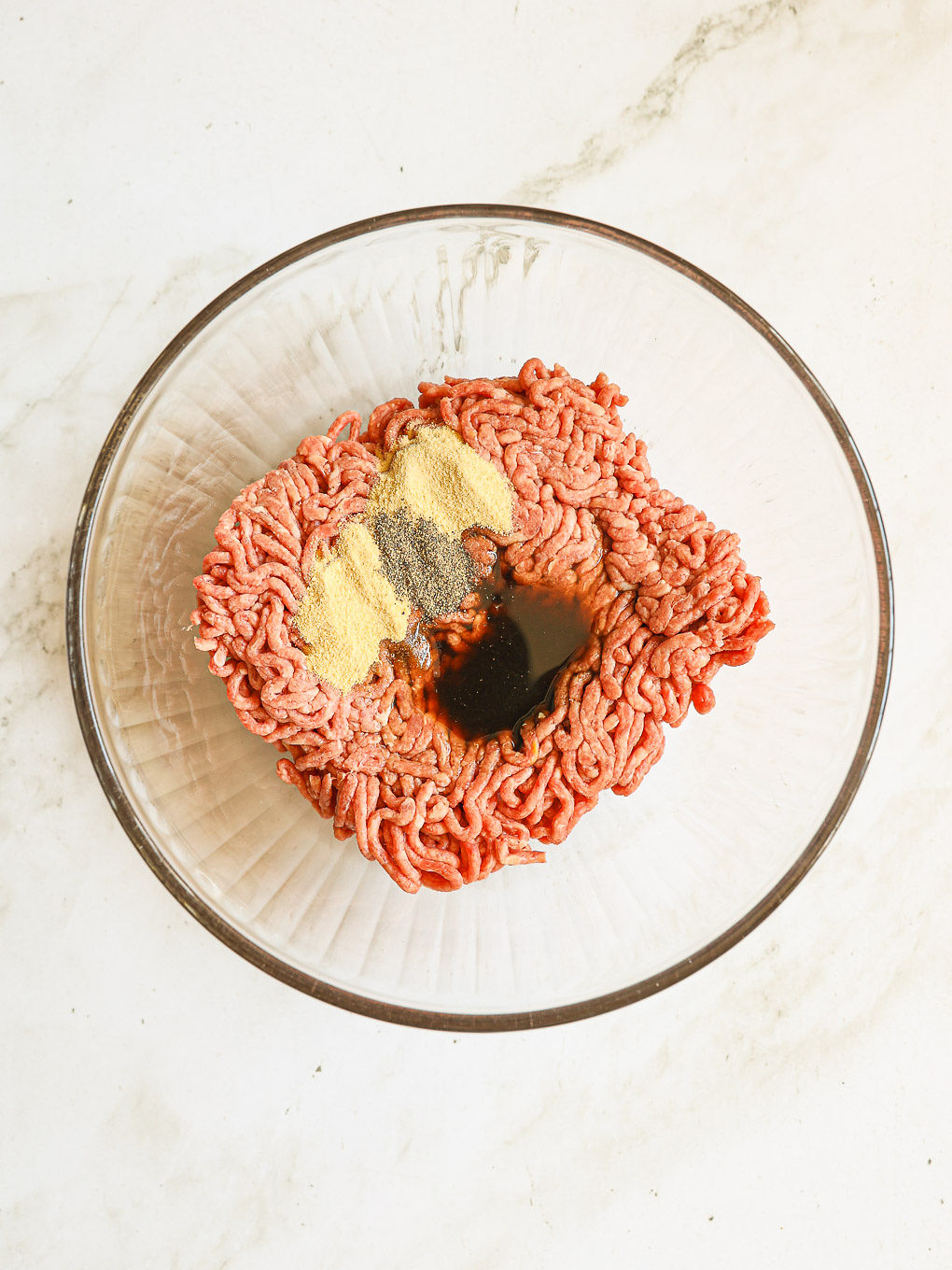ground beef with spices in glass bowl.