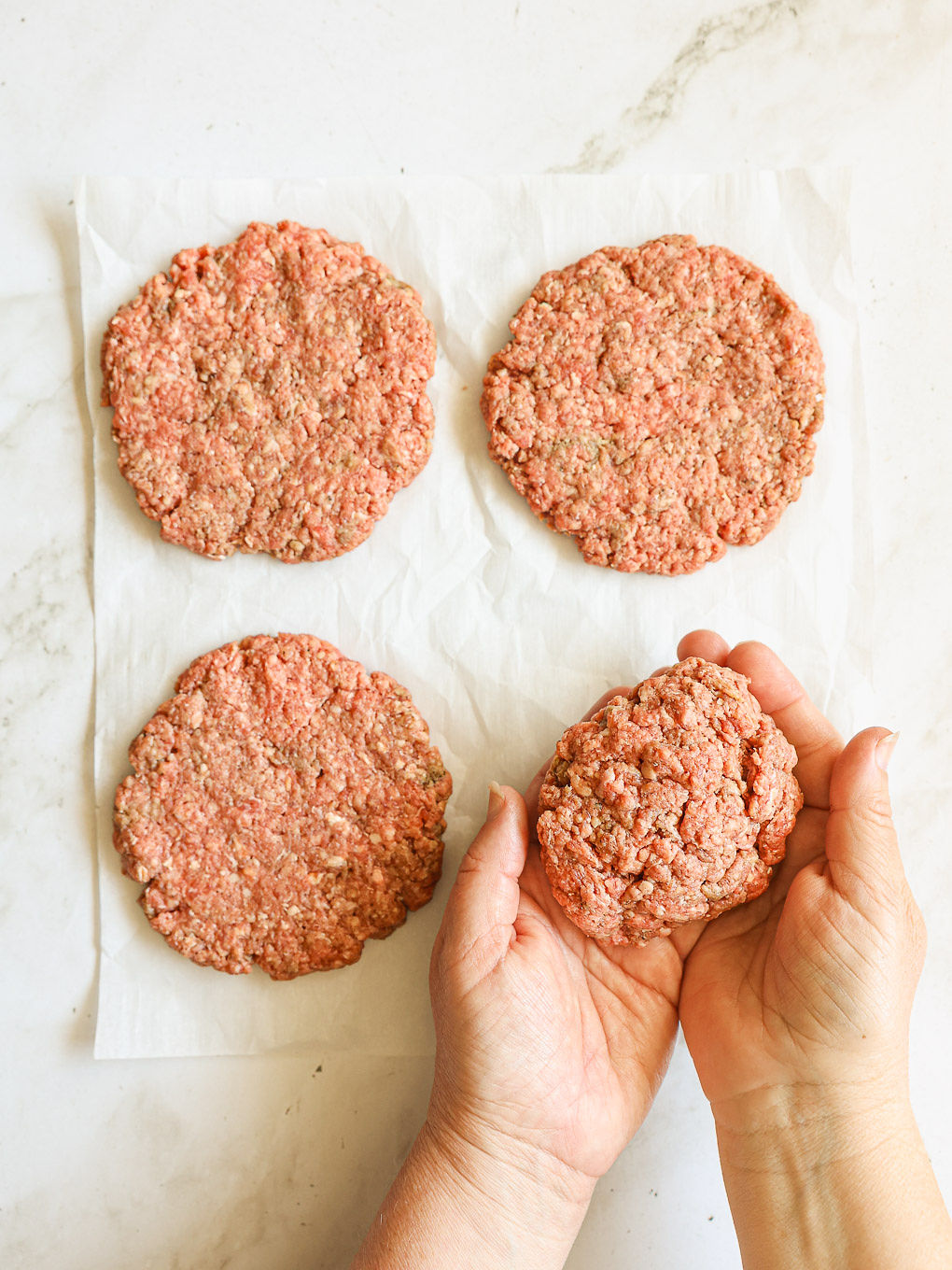 shaped beef patties on a parchment paper.