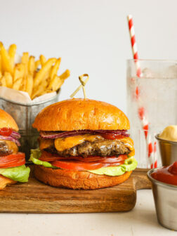 homemade beef burger on a board with toppings.