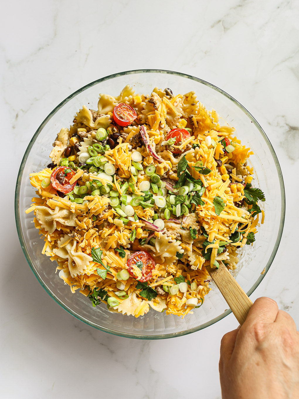 tossed pasta salad in a glass bowl.