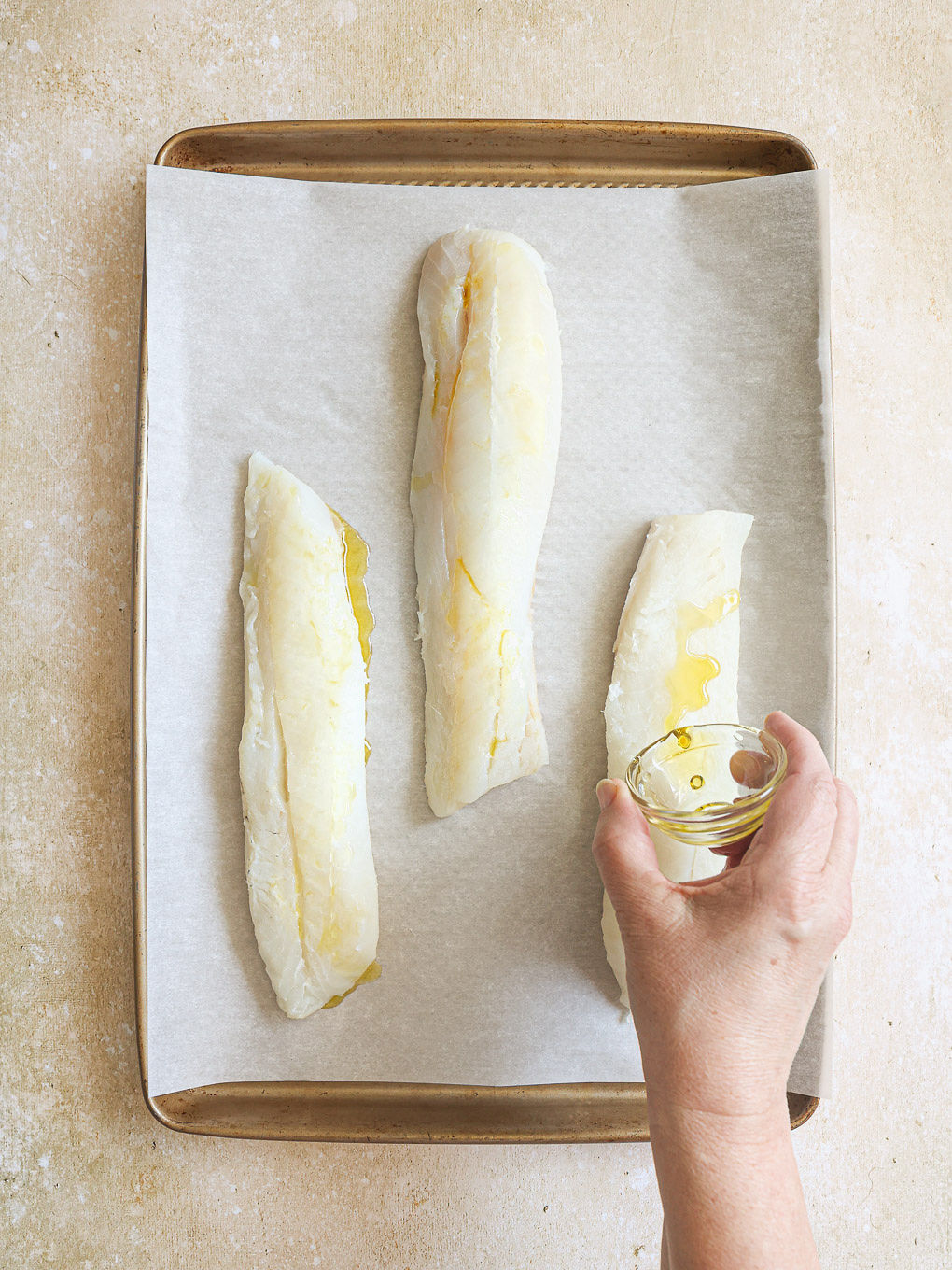 cod fillets on a baking sheet topped with oil.