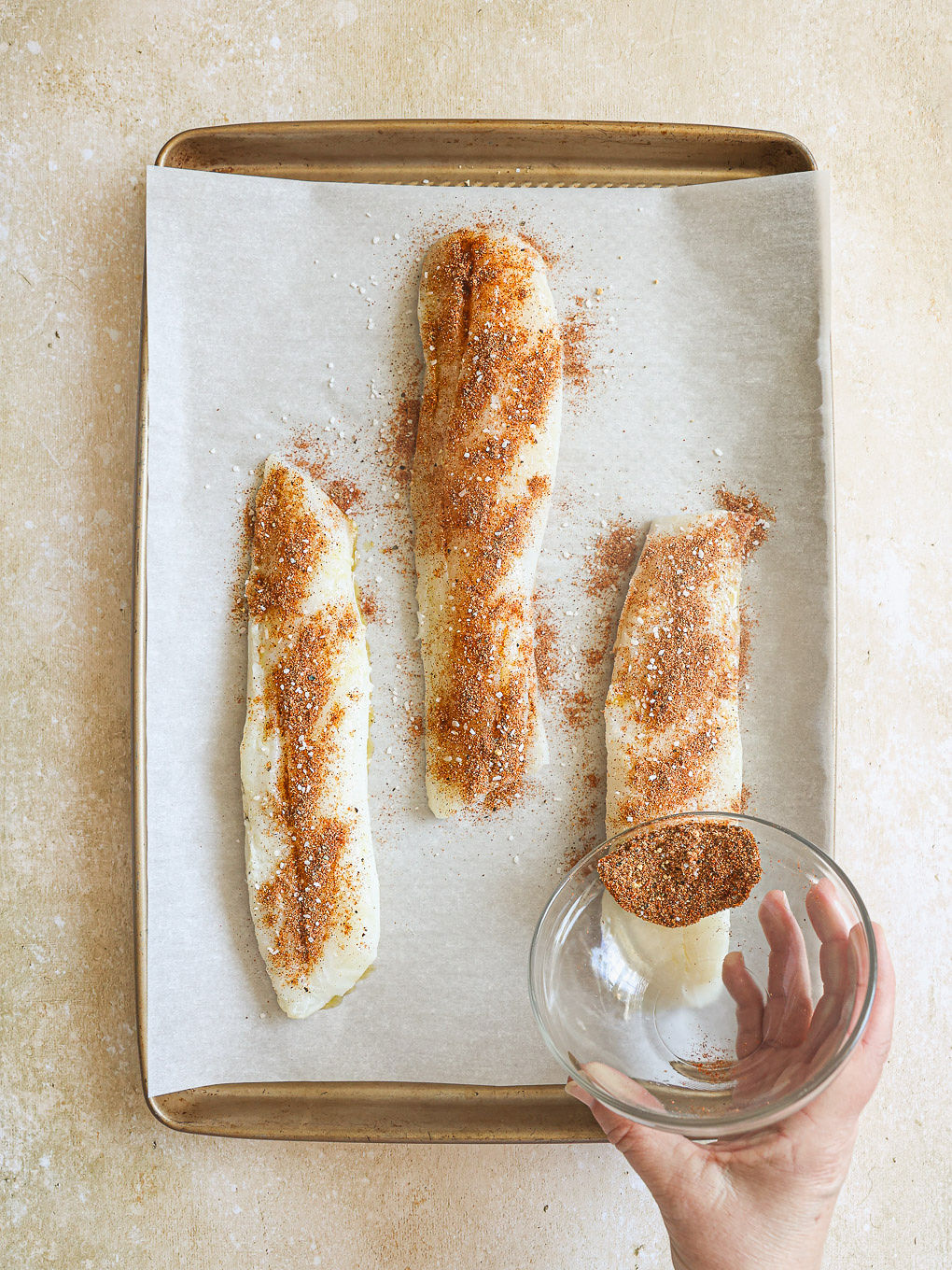cod fillets topped with dry spice mixture on a baking sheet.