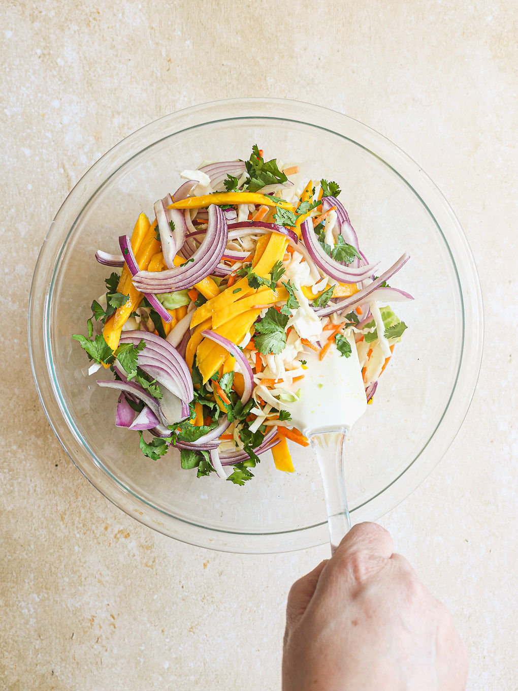 slaw mix with mango and cilantro in a mixing bowl.