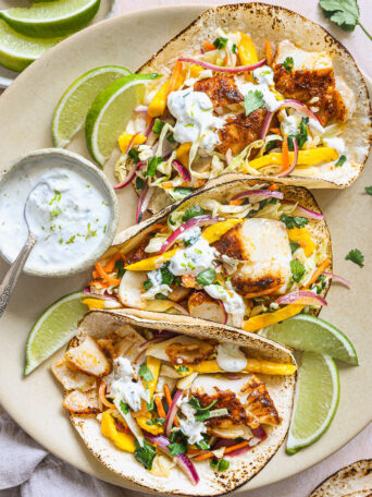 fish tacos topped with mango slaw on a platter.