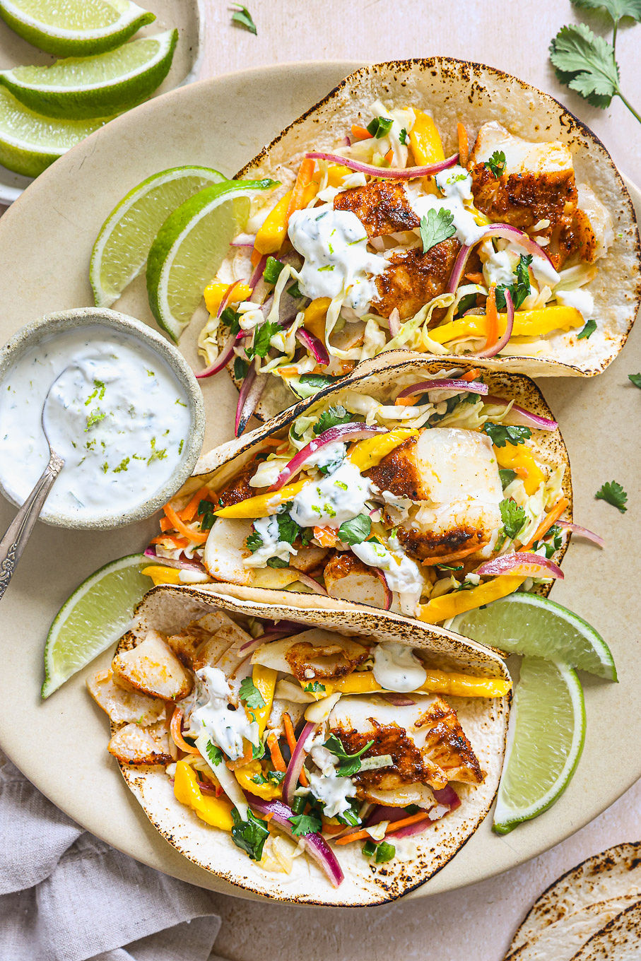 fish tacos topped with mango slaw on a platter.