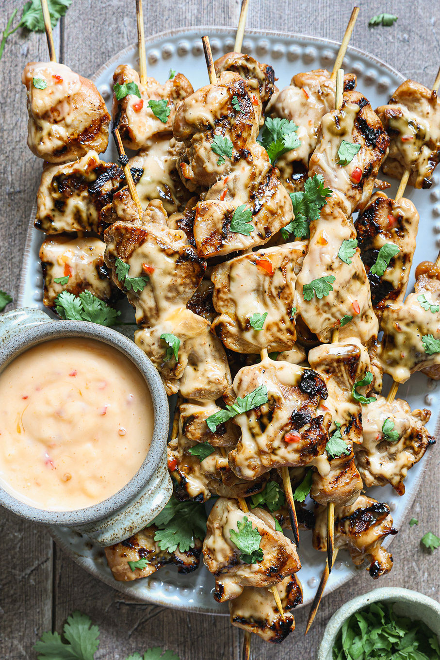 
chicken skewers with sauce over them on a platter.