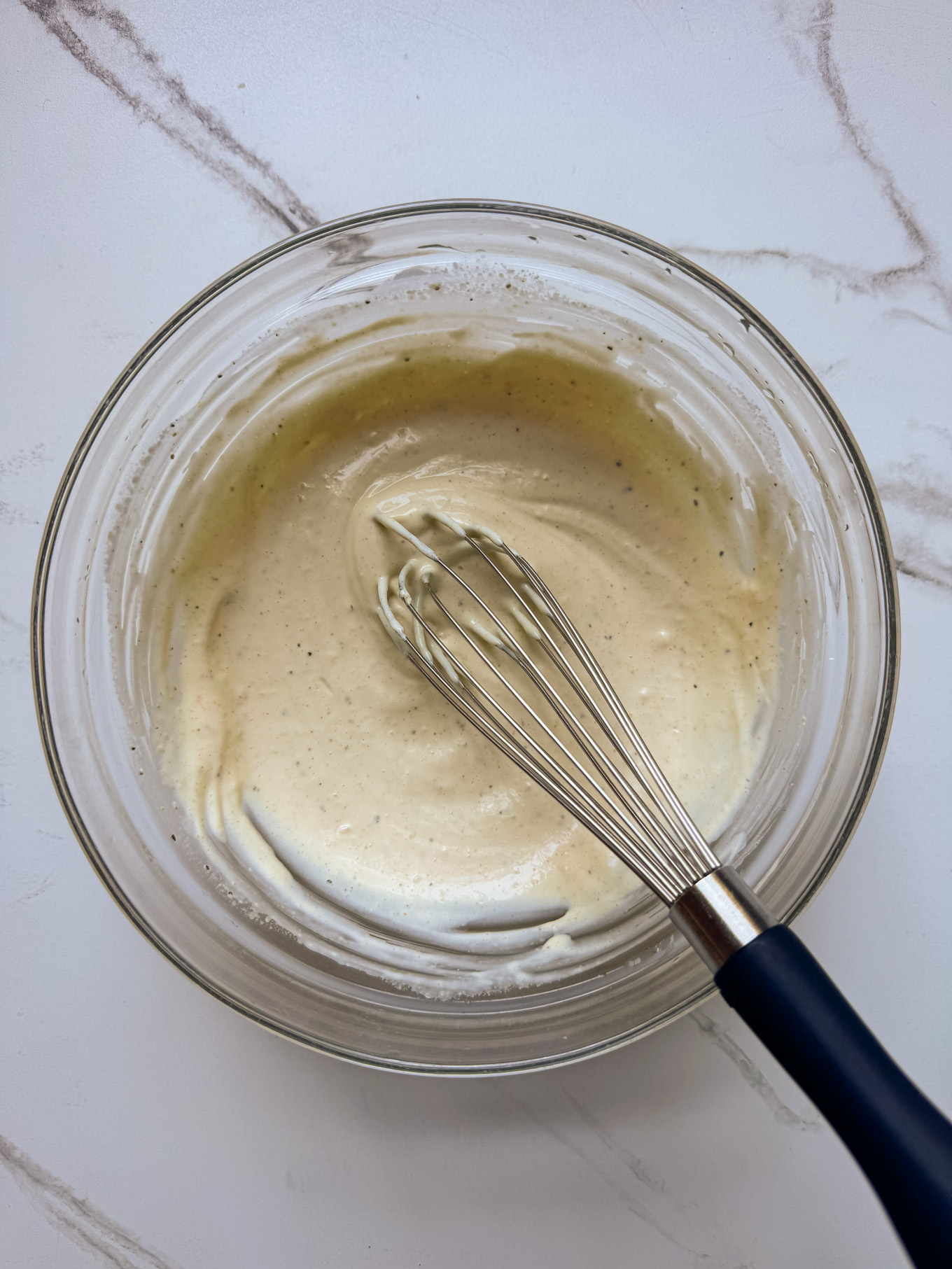 whisked dressing in a glass bowl.