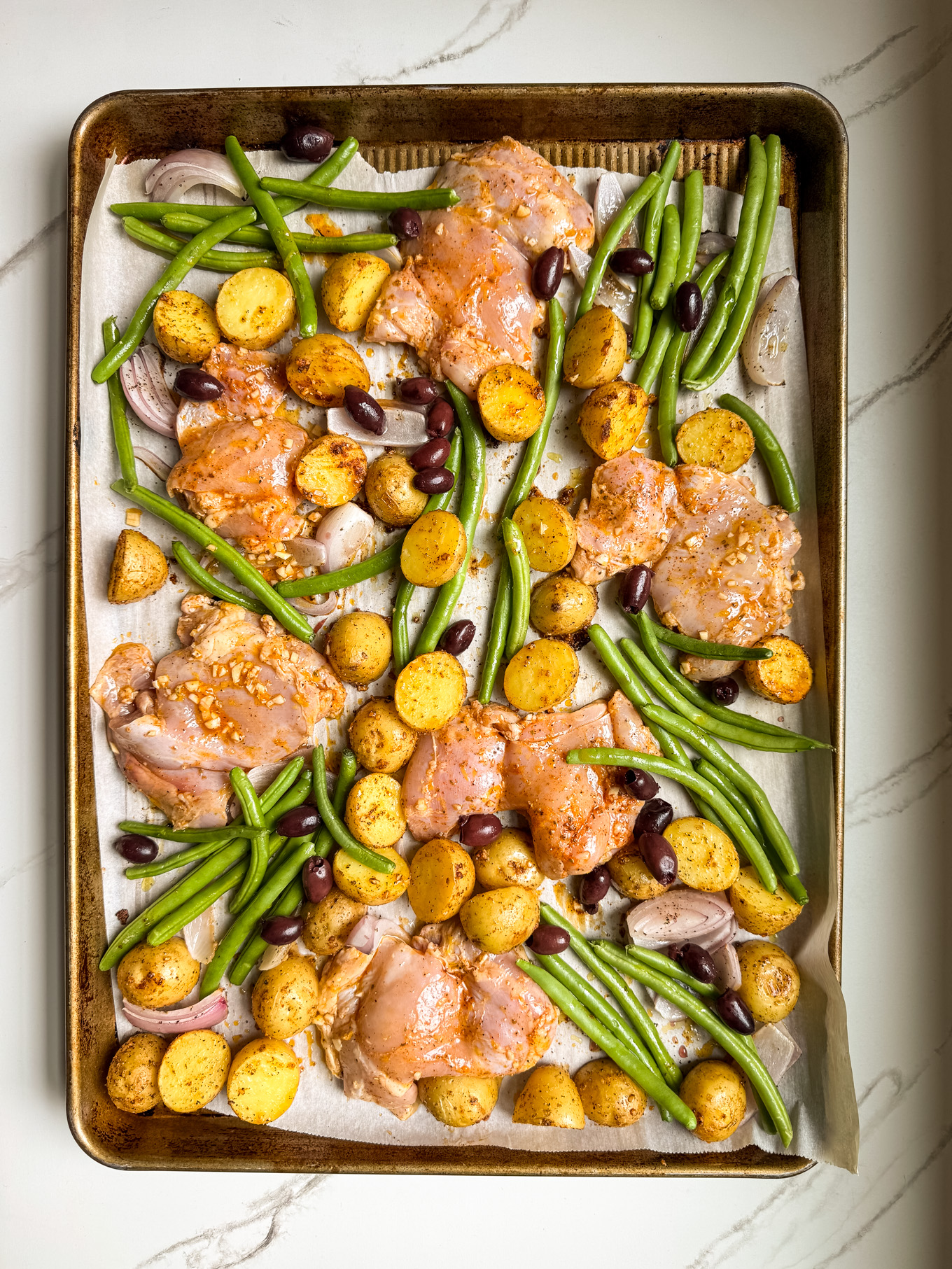 chicken with potatoes and greens on a sheet pan.