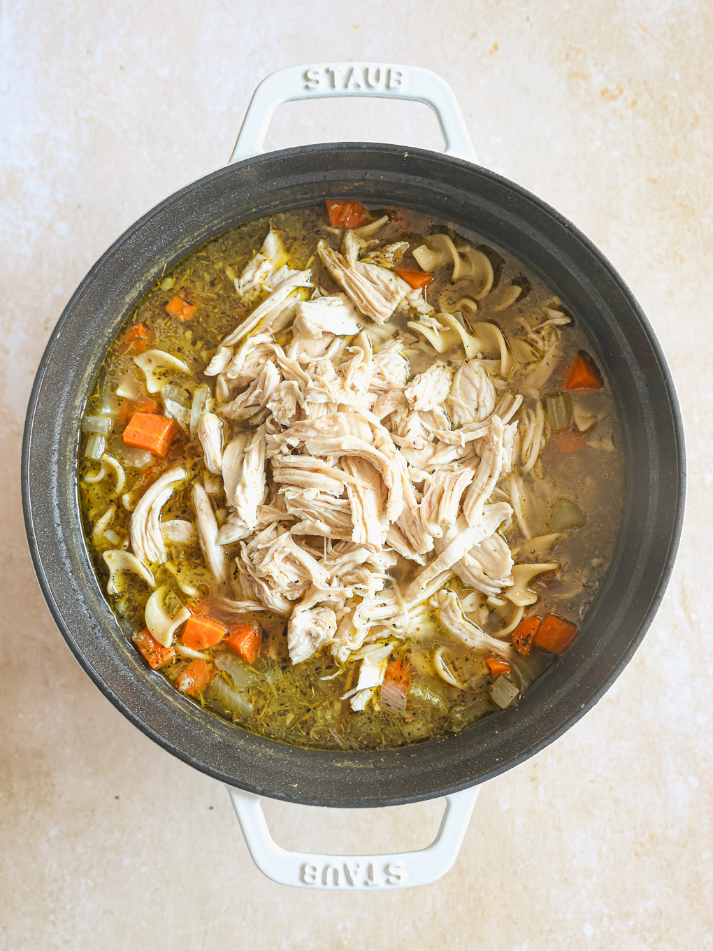 chicken soup in a pot with shredded chicken.
