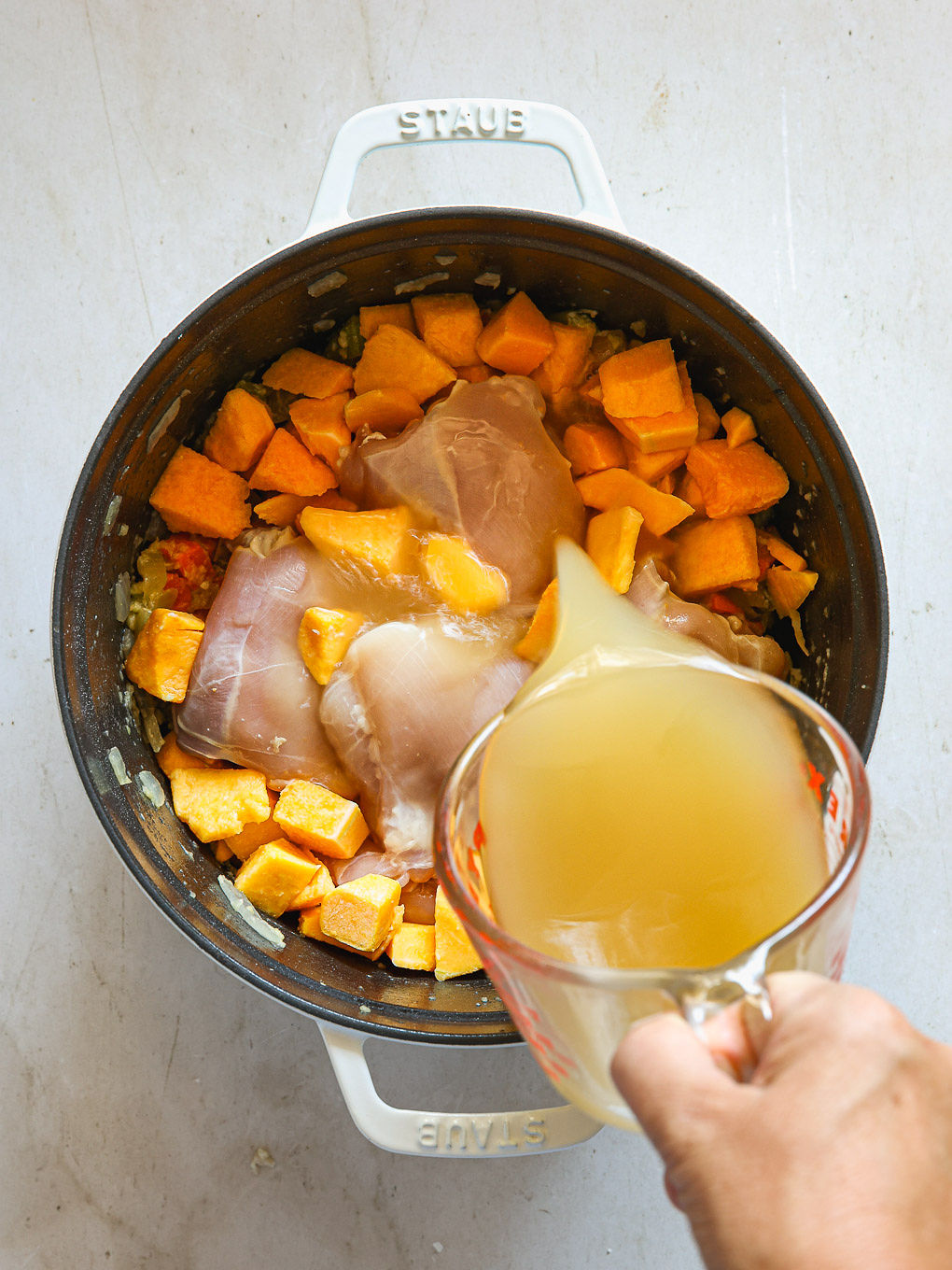 chicken with butternut squash and stock in a pot.