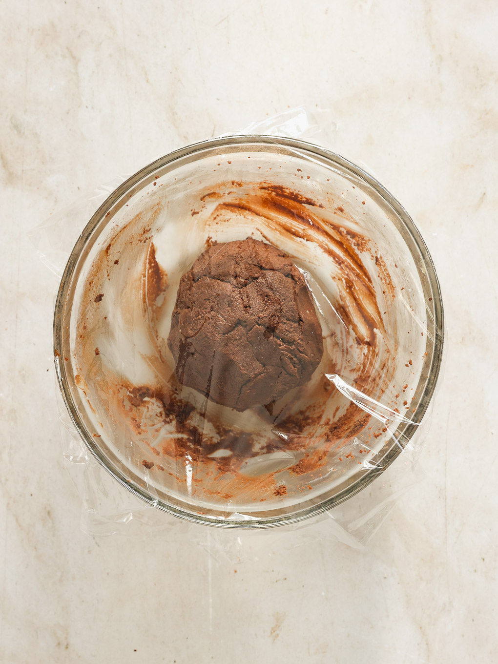 Cookie dough in a bowl covered with plastic wrap.