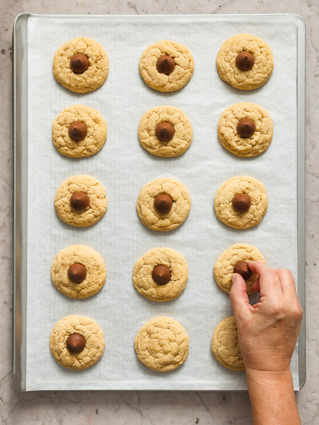 baked cookies on a baking sheet with kiss candy inside.
