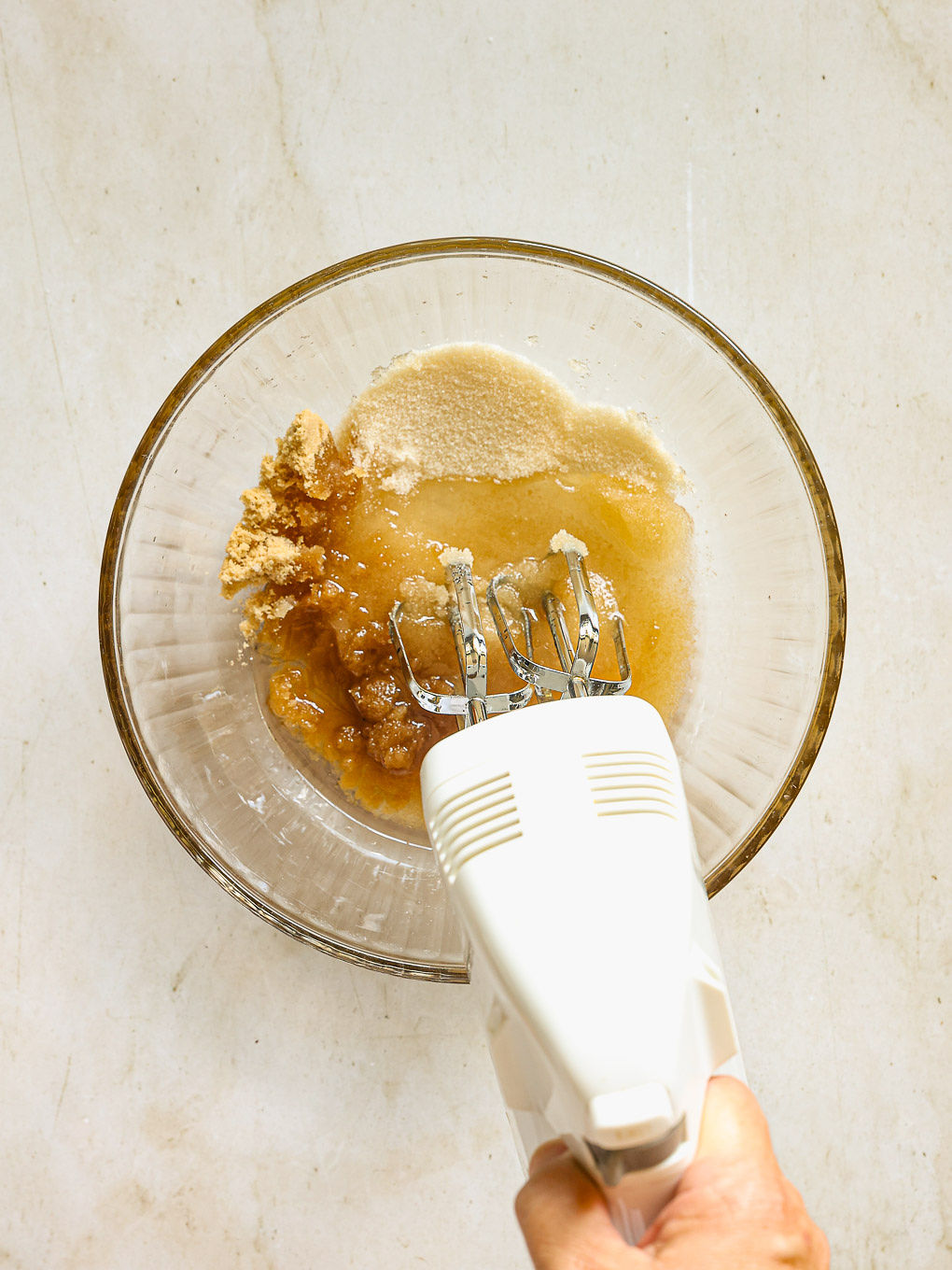wet ingredients with mixer in a glass bowl.