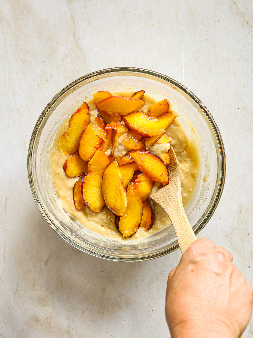 sliced peaches with muffins batter in a bowl.
