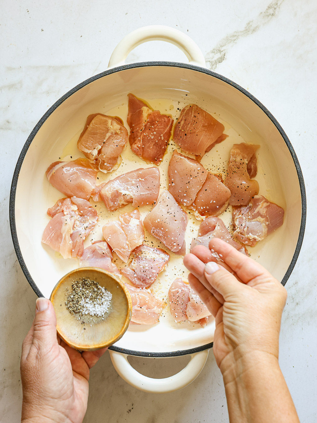 chicken pieces in a skillet with salt and pepper.