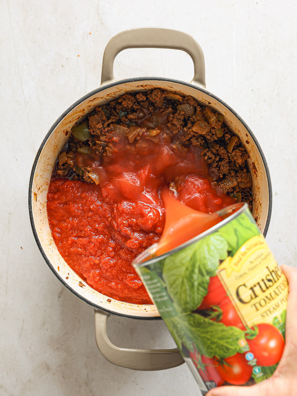 crushed tomatoes going inside a pot.